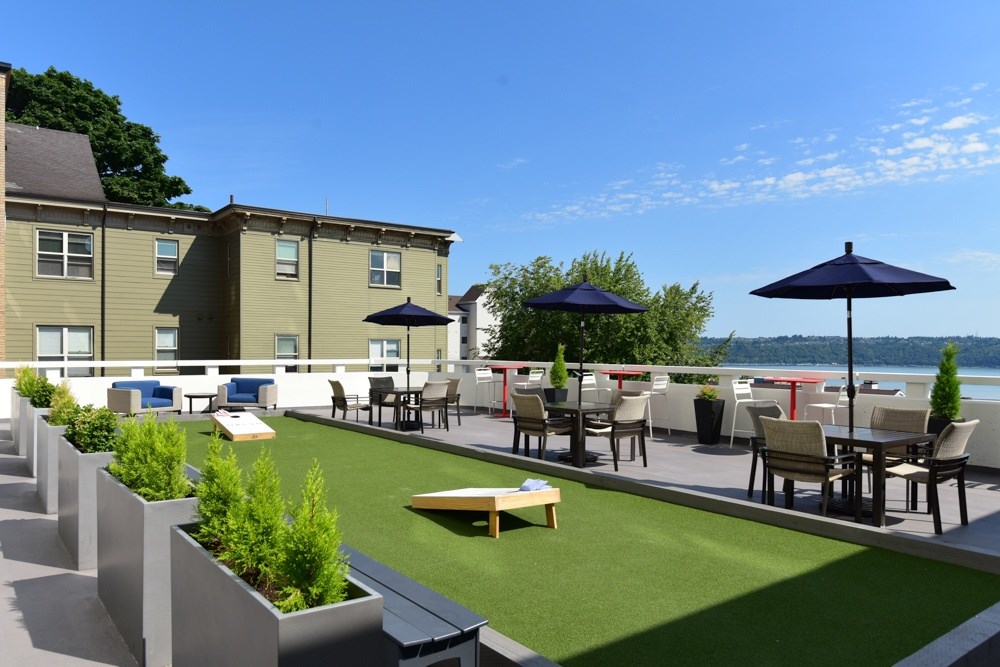 A patio with tables and chairs overlooking a body of water.