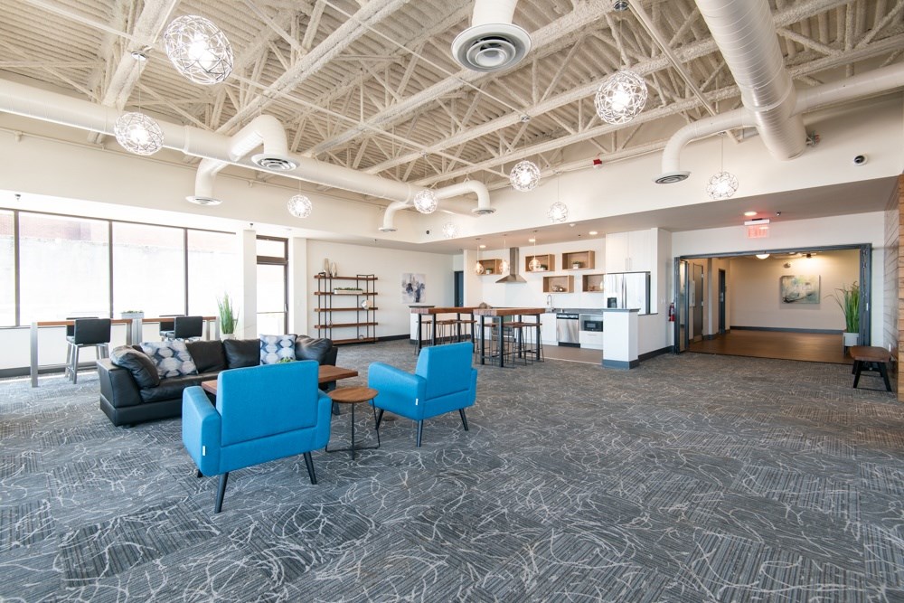 A spacious room with a patterned carpet and a variety of seating options.