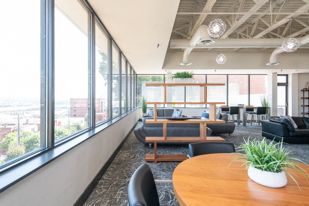 A modern office space with a long wooden table and black chairs.