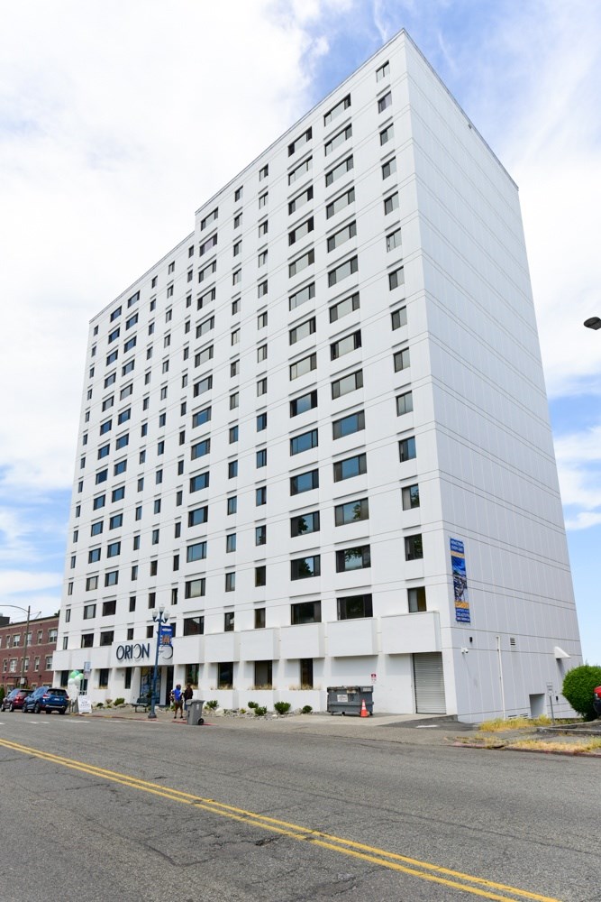 A tall white building with a blue sign on the bottom right.