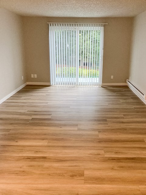 A room with wooden flooring and a sliding glass door.