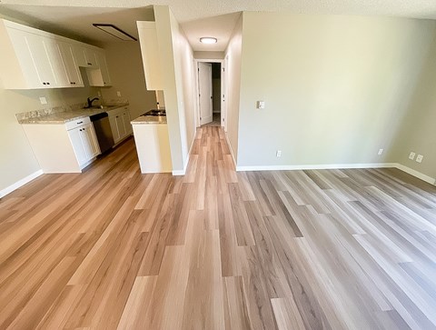 A kitchen with white cabinets and a wooden floor.