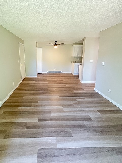 A long hallway with wood flooring and a ceiling fan.