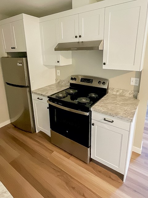A kitchen with a stove top oven and a refrigerator.