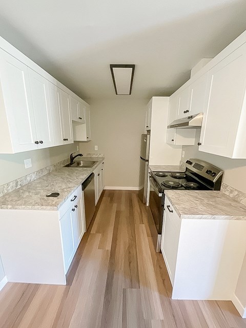A kitchen with white cabinets and a marble countertop.