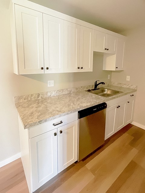 A kitchen with white cabinets and a granite countertop.