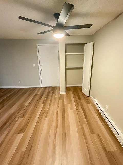 A room with a ceiling fan and wooden flooring.