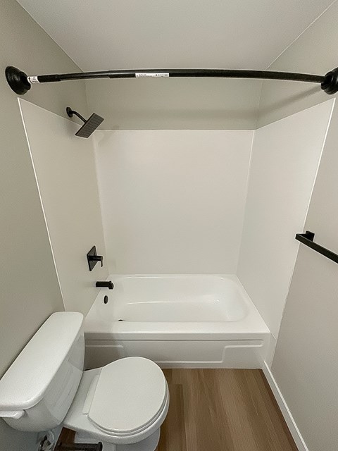 A white toilet sits next to a white bathtub in a small bathroom.