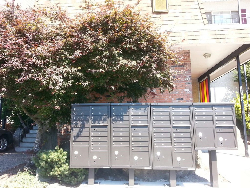 A grey mailbox with a red door in the background.