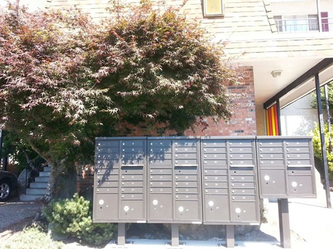 A grey mailbox with a red door in the background.