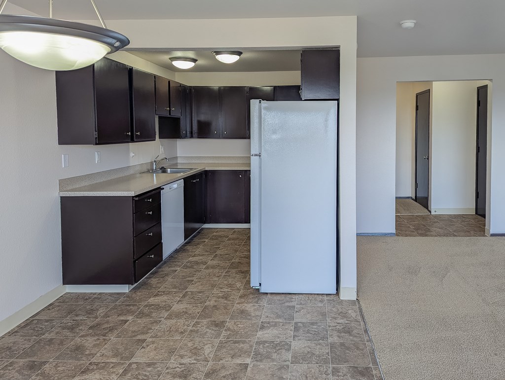 A kitchen with a white refrigerator and brown cabinets.