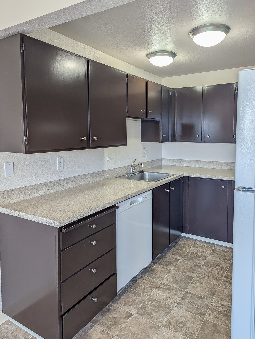 A kitchen with brown cabinets and a white fridge.