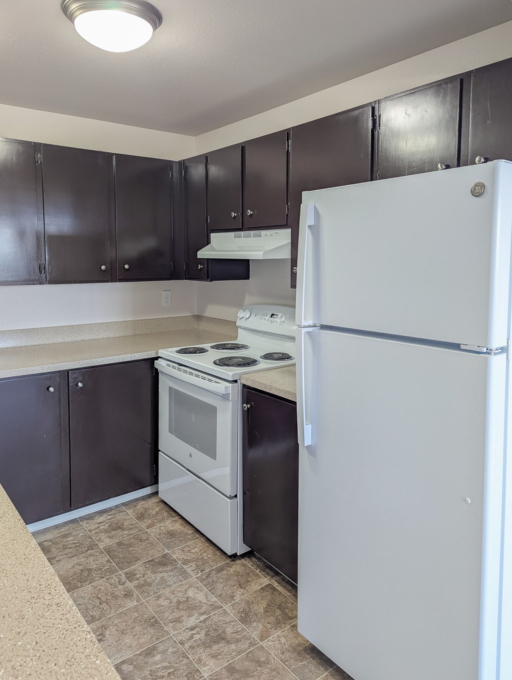 A white refrigerator stands in a kitchen with black cabinets.