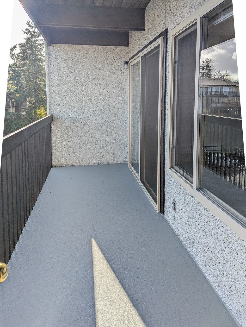 A balcony with a black railing and a white speckled wall.