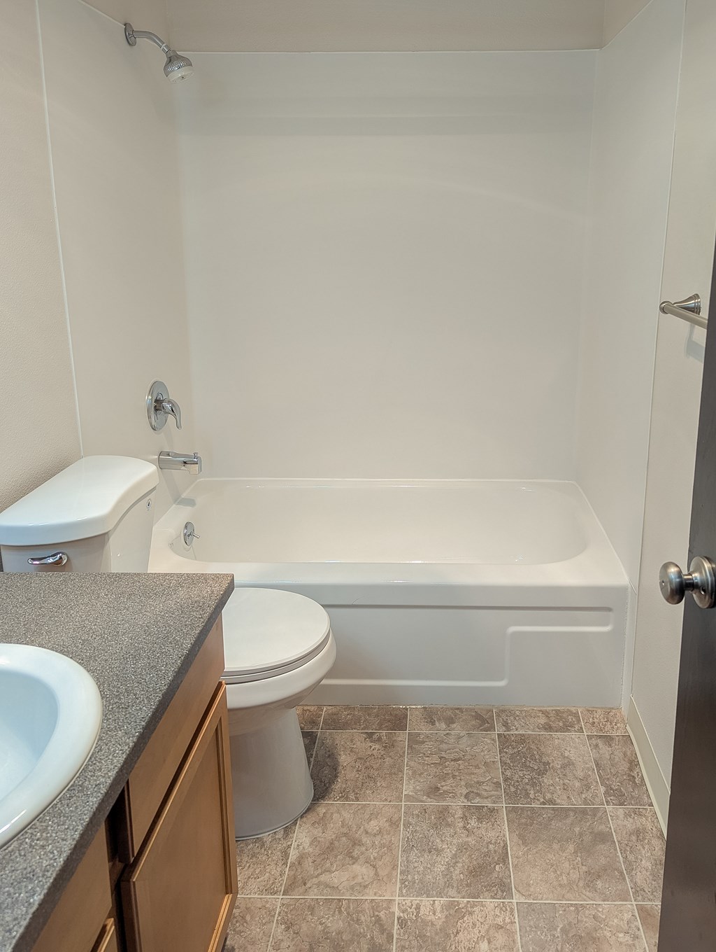 A white toilet sits next to a white bathtub in a bathroom.