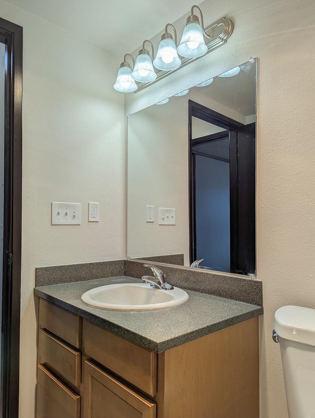 A bathroom with a sink, mirror, and lights.