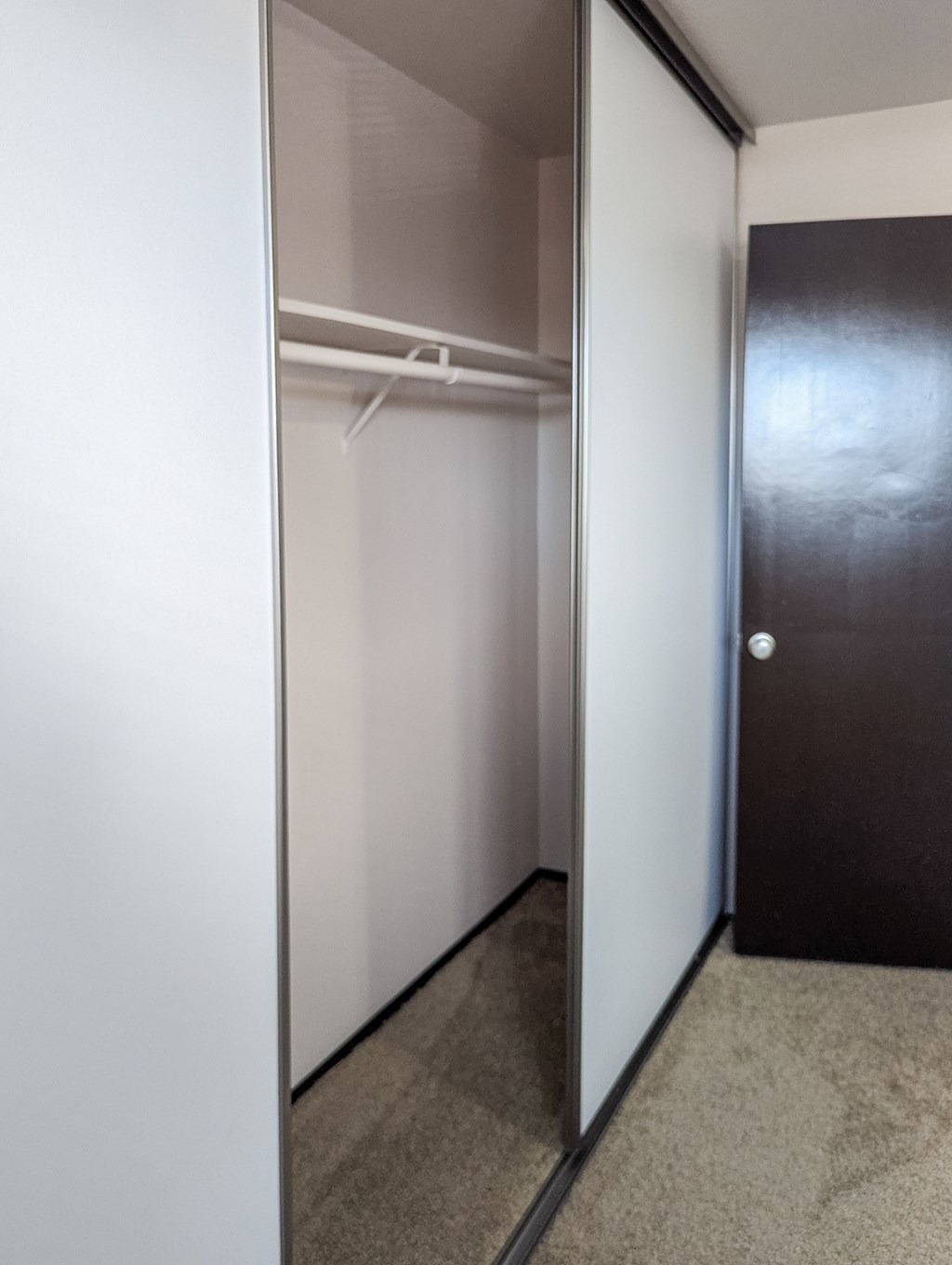 A hallway with a black door and a white wall.