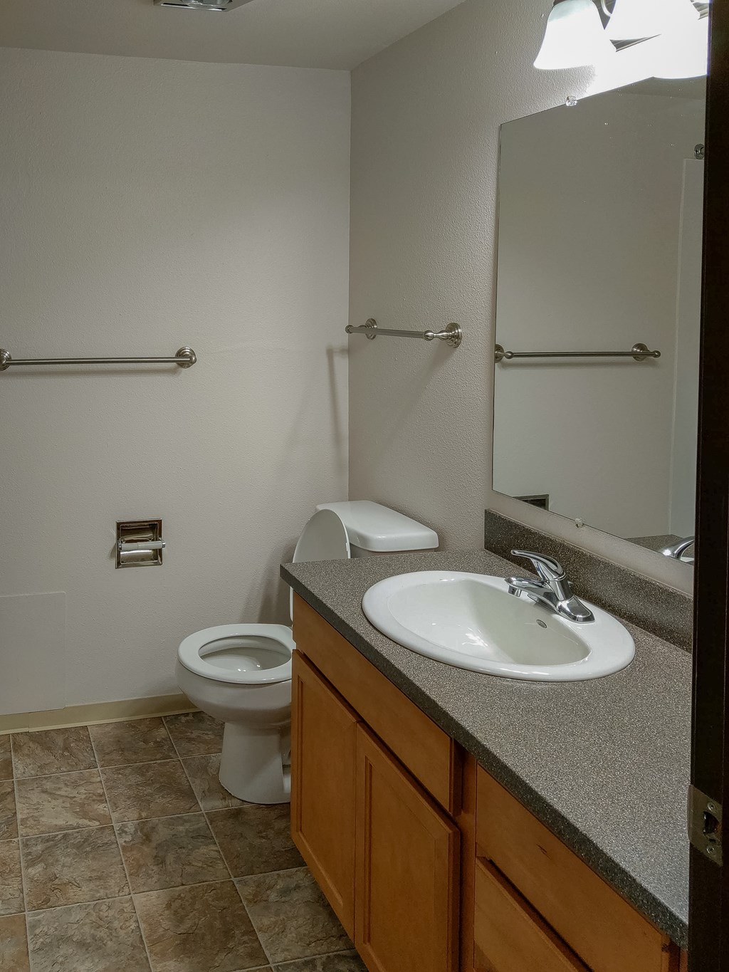 A bathroom with a toilet, sink, and grab bars.
