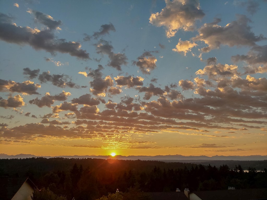 The sun is setting behind the clouds in the sky.