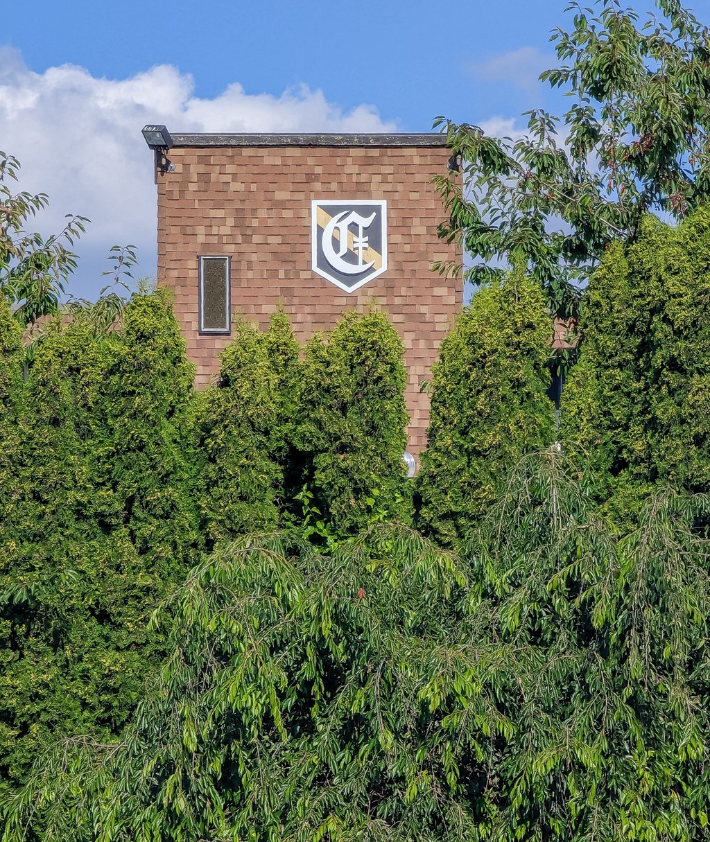 A building with a logo on it is surrounded by greenery.