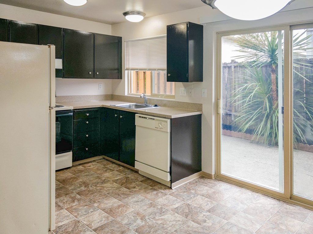 A kitchen with black cabinets and a white refrigerator.