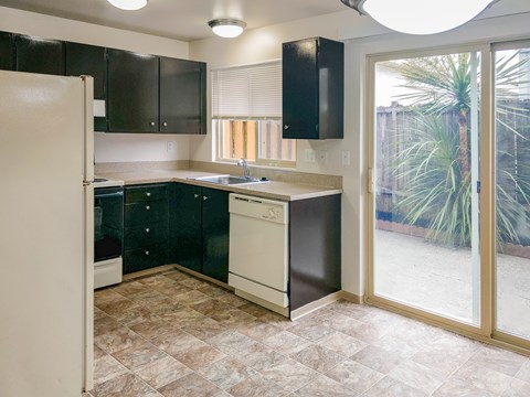 A kitchen with black cabinets and a white refrigerator.