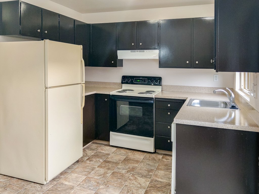 A kitchen with black cabinets and a white refrigerator.