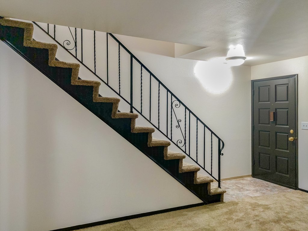 A staircase with a black metal railing and beige carpeted steps.