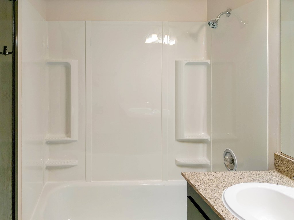 A white bathroom with a tub, sink and shower.
