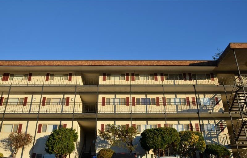A large building with a red roof and white walls with balconies.