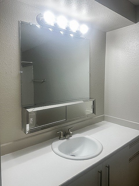 A bathroom sink under a mirror with lights above it.