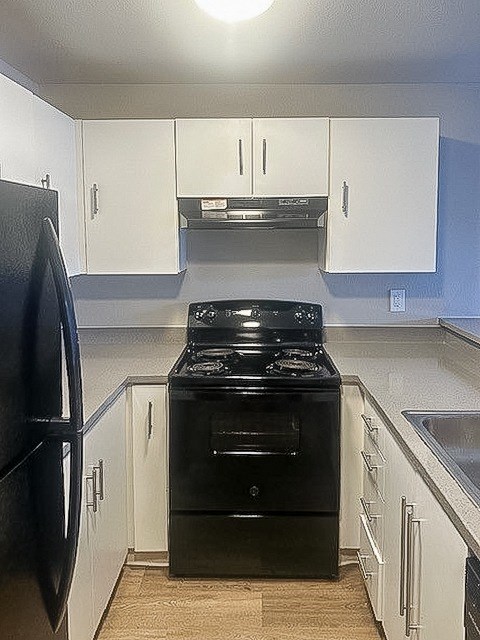 A black stove and oven in a kitchen with white cabinets.