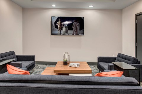 A living room with a grey couch and a painting on the wall.