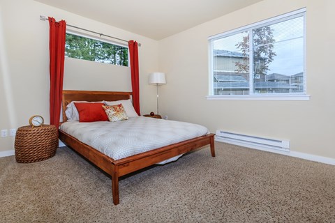 A bedroom with a bed, carpet, and a window.