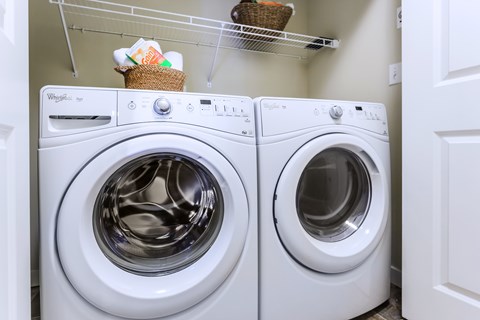 Two white Whirlpool washing machines in a laundry room.