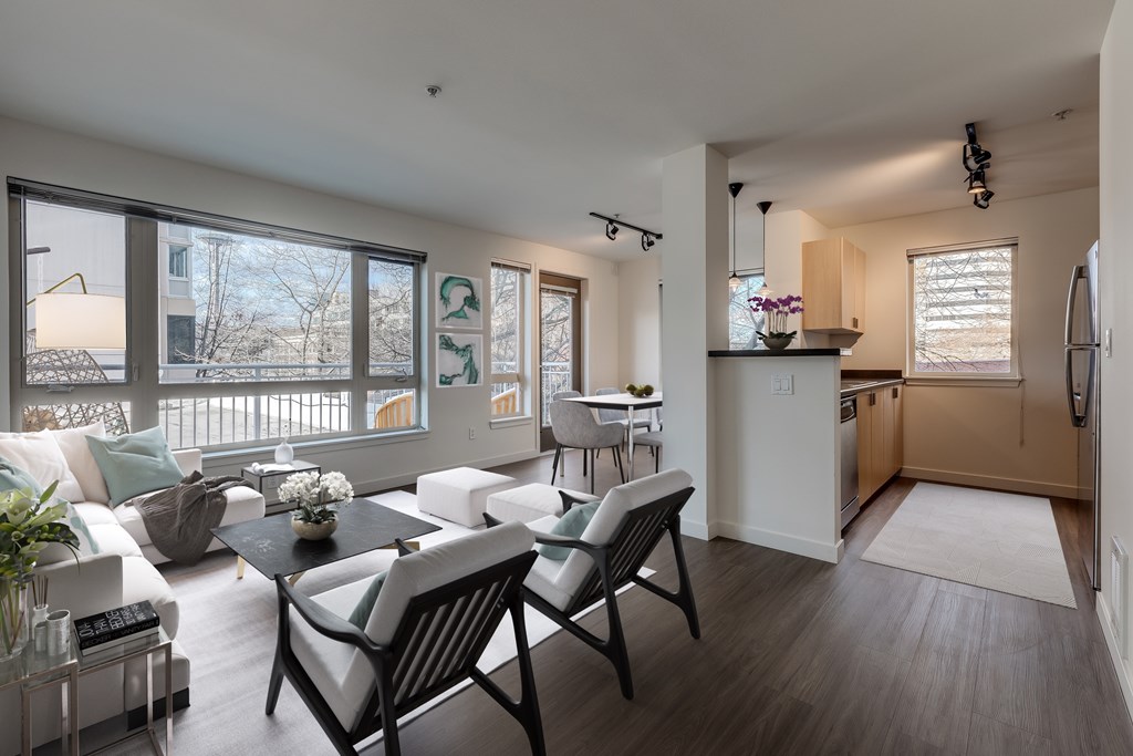 A modern living room with a dining area and kitchen in the background.