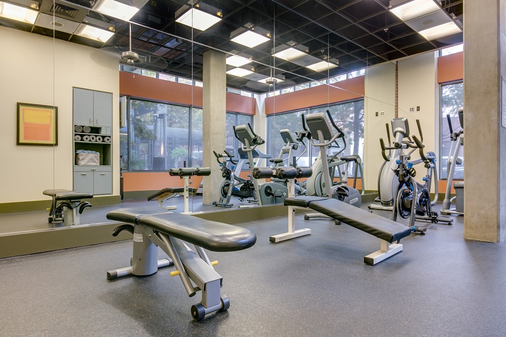 A gym with a variety of equipment including treadmills, weights, and exercise machines.