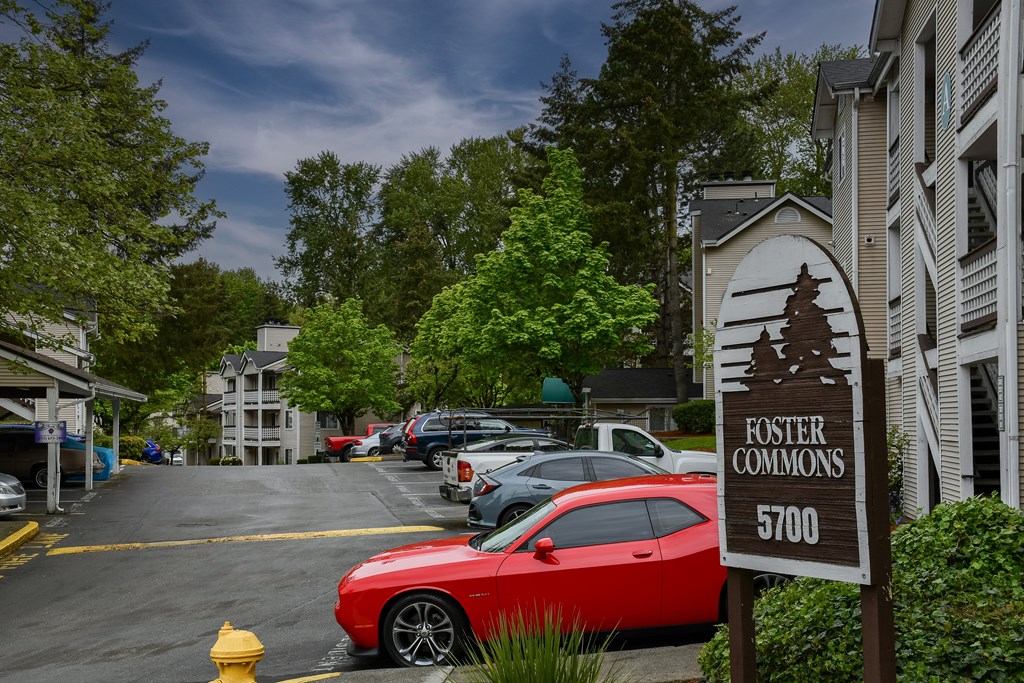 A red car is parked in a parking lot with a sign that says
