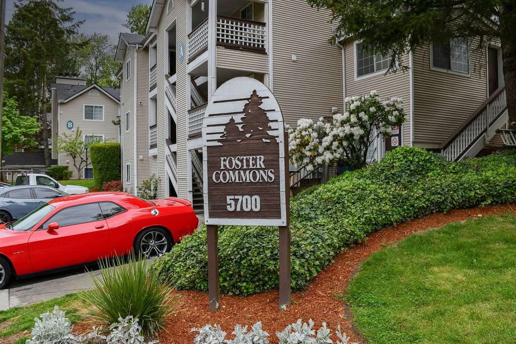A red car is parked in front of a building with a sign that says "Foster Commons 5700".