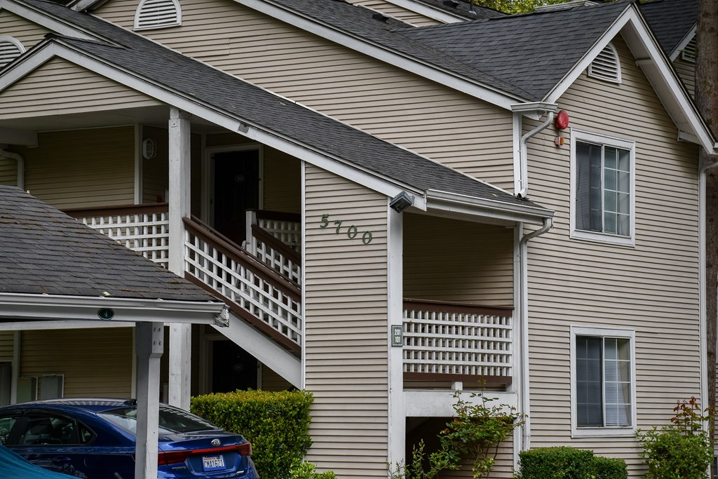 A car is parked in front of a house with the number 5705 on it.