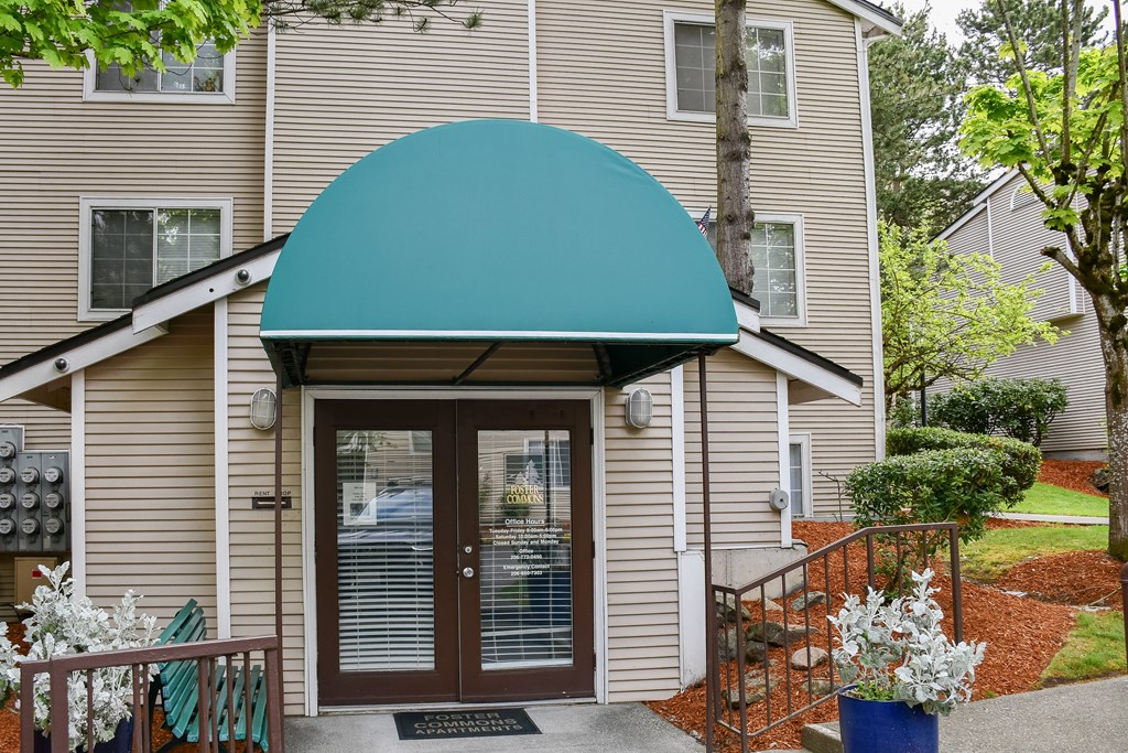 A beige building with a blue awning and a glass door.