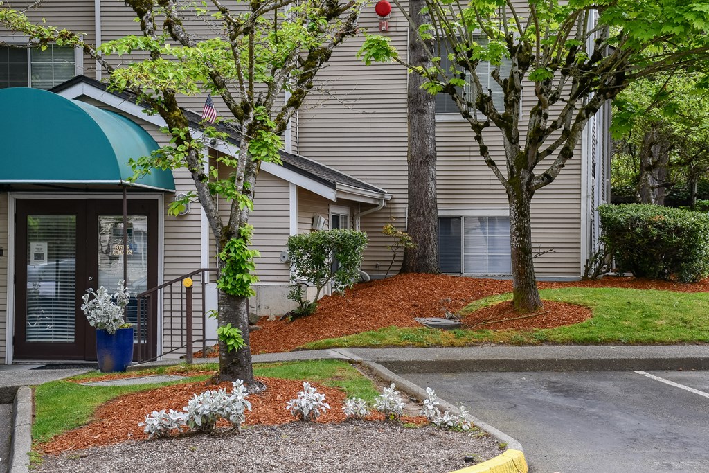 A building with a green awning and a tree with white flowers in front.