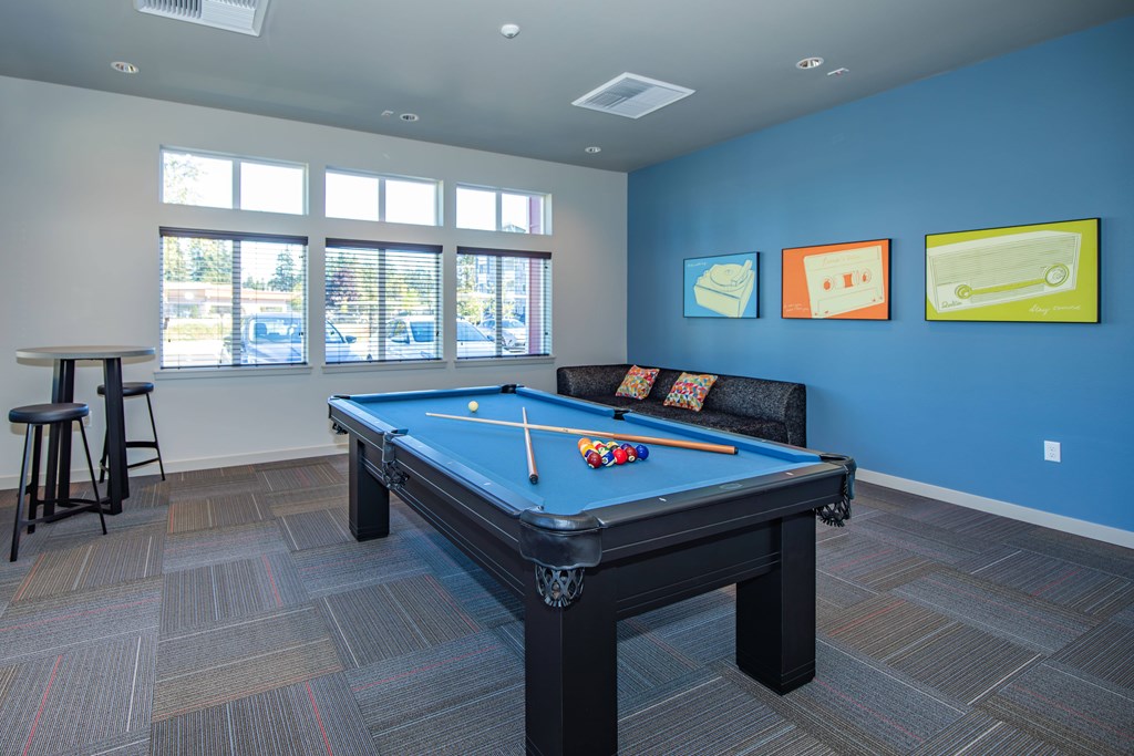 A pool table in a room with a blue wall and a window.