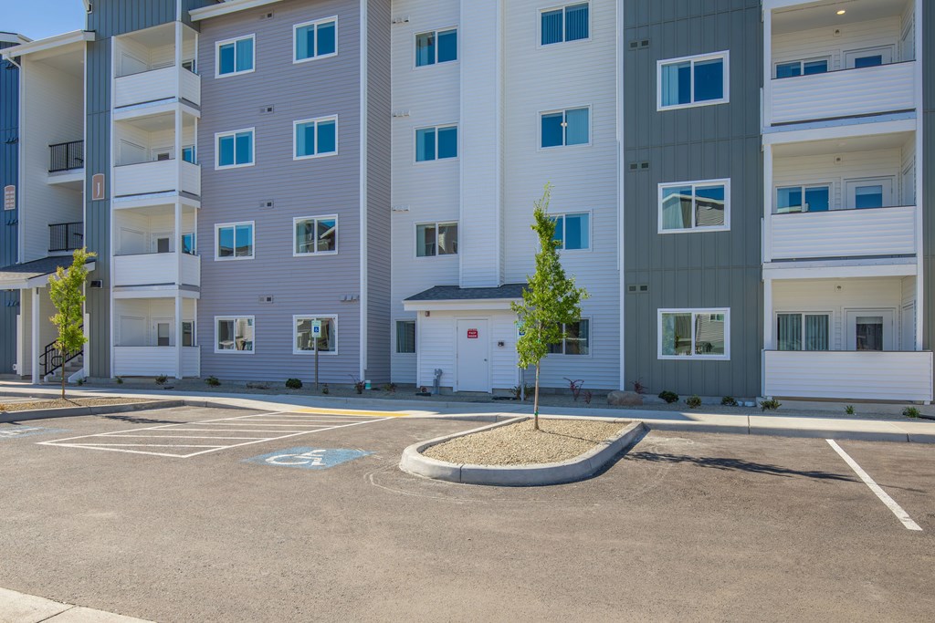 A parking lot in front of a multi-story apartment building.
