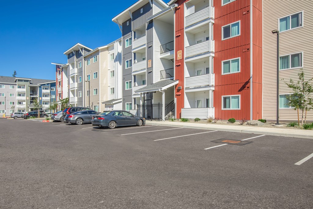A parking lot in front of a multi-story apartment building.