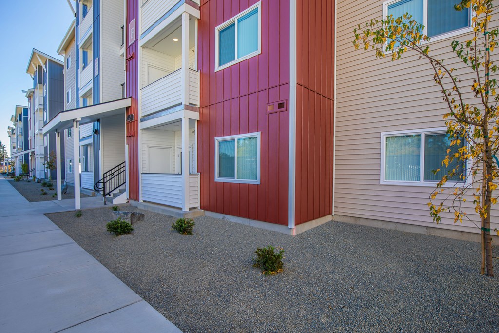 A red and beige building with a tree in front.