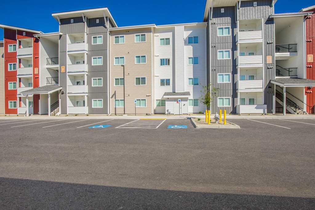 A parking lot in front of a multi-story apartment building.