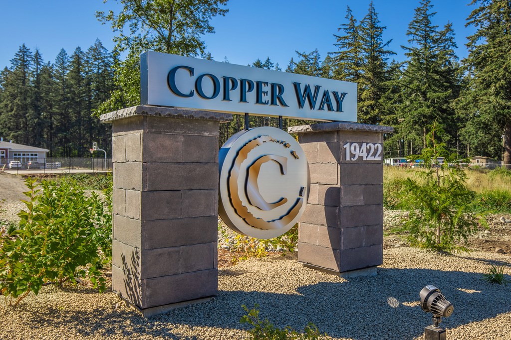 A sign that says Copper Way stands in front of a forest.