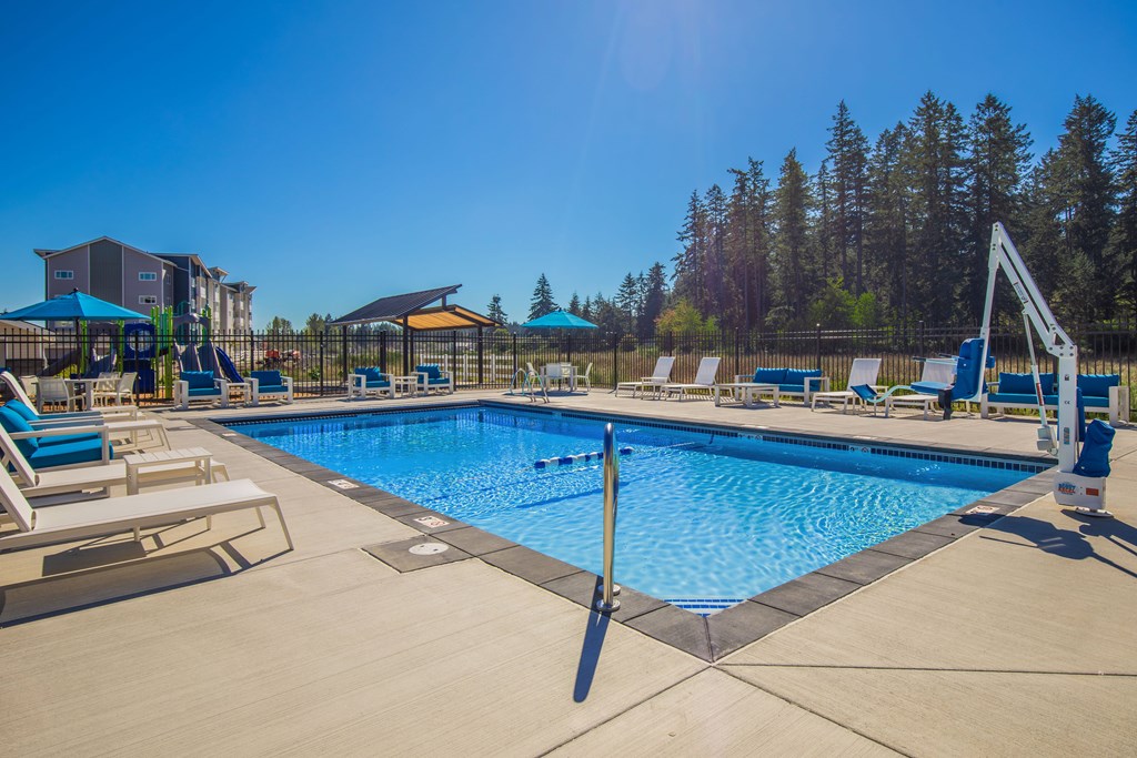 A large swimming pool with a diving board and lounge chairs.