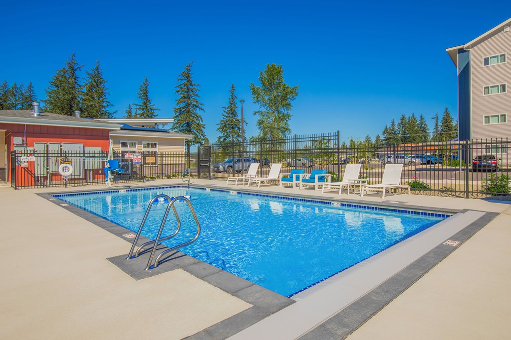 A swimming pool with a diving board and lounge chairs.